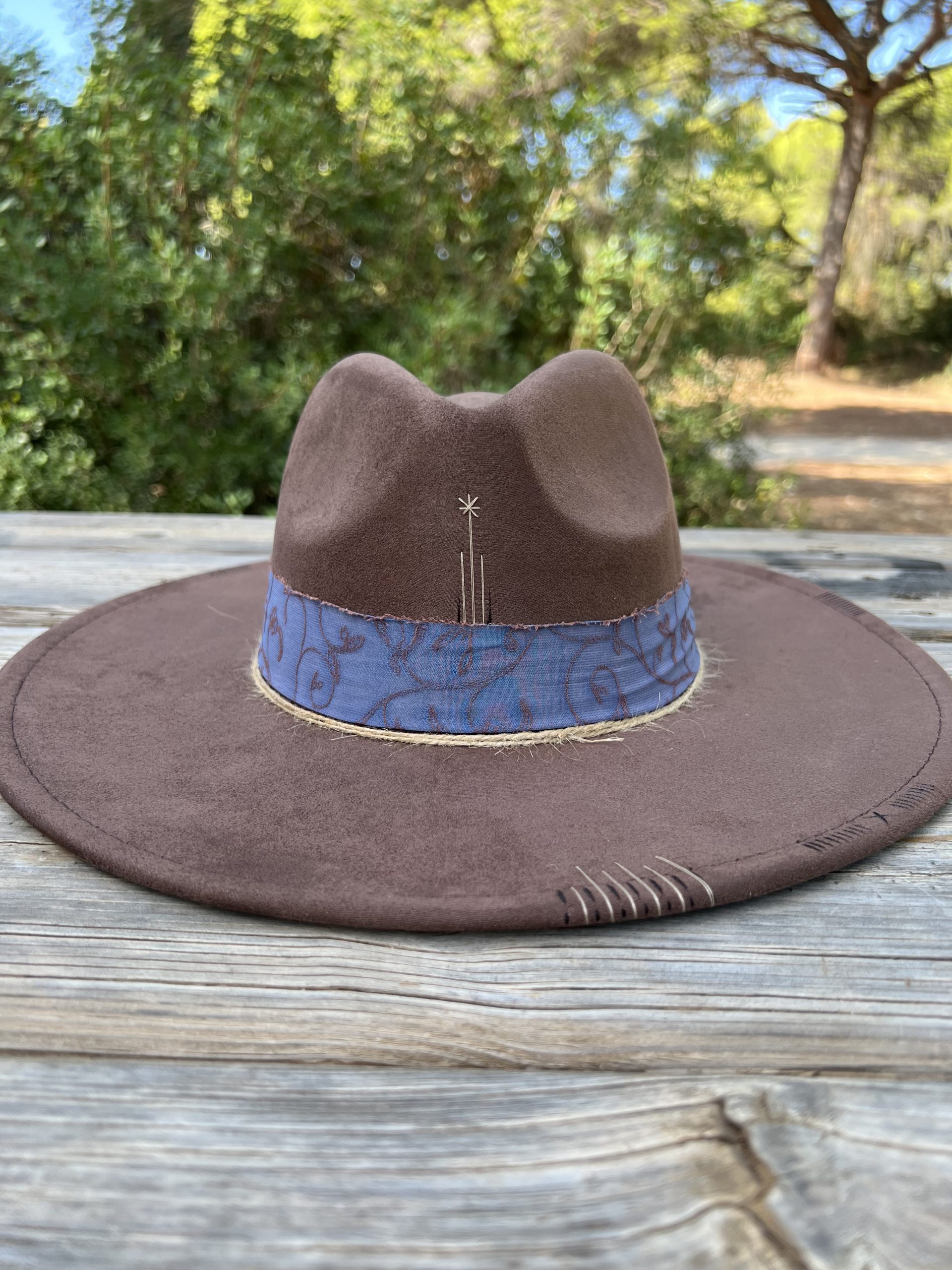 Sombrero marrón Nature One of a Kind con cinta azul, bordados artesanales y grabados decorativos.