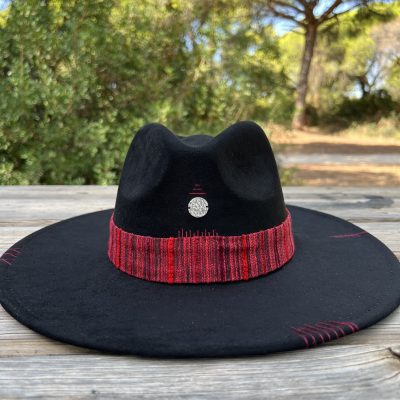 Sombrero negro artesanal Nature One of a Kind con cinta en tonos rojizos, bordados y dije plateado central.