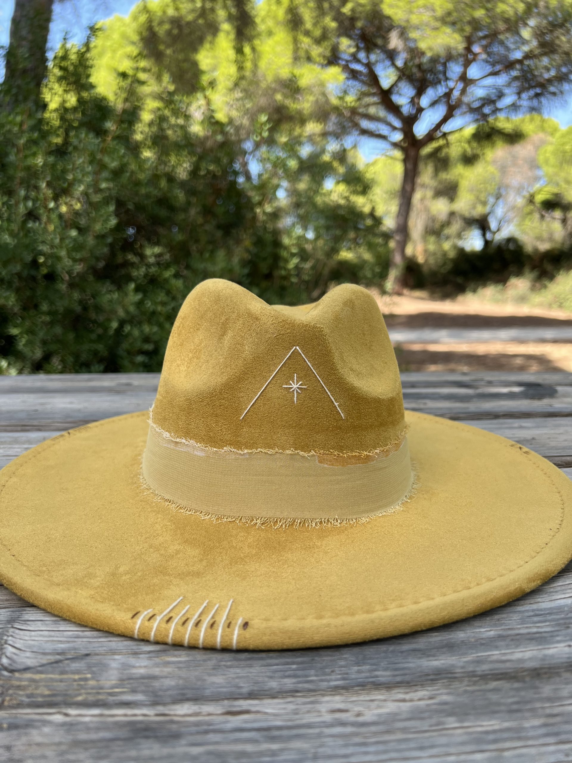 Sombrero mostaza Nature One of a Kind con bordado beige en forma de triángulo en el frontal y grabados decorativos.